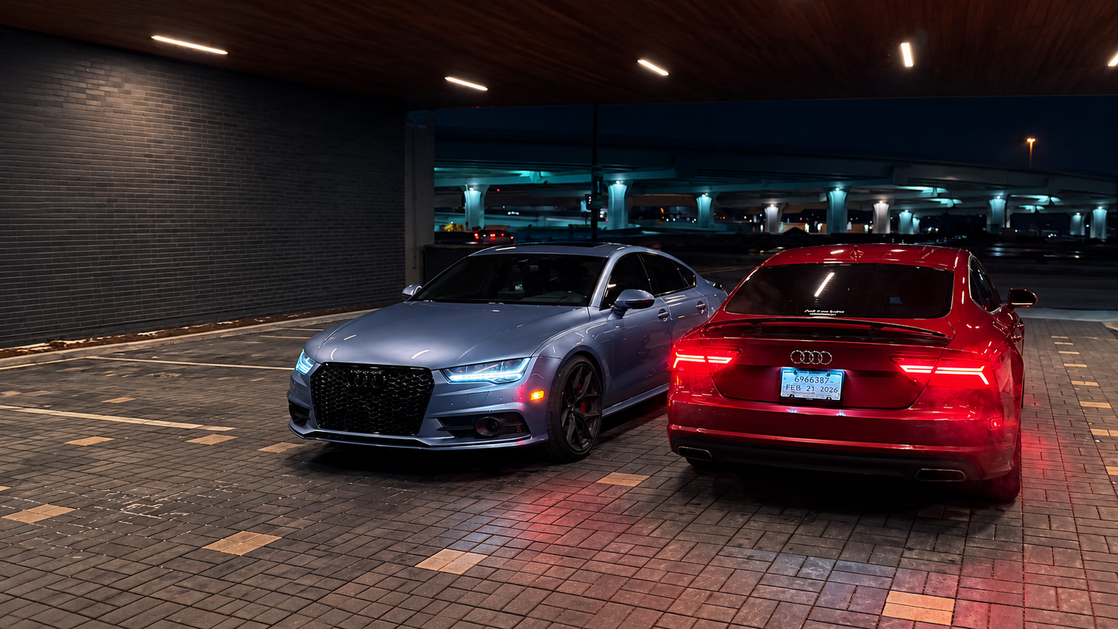 Blue and red Audi performance sedans parked together at night